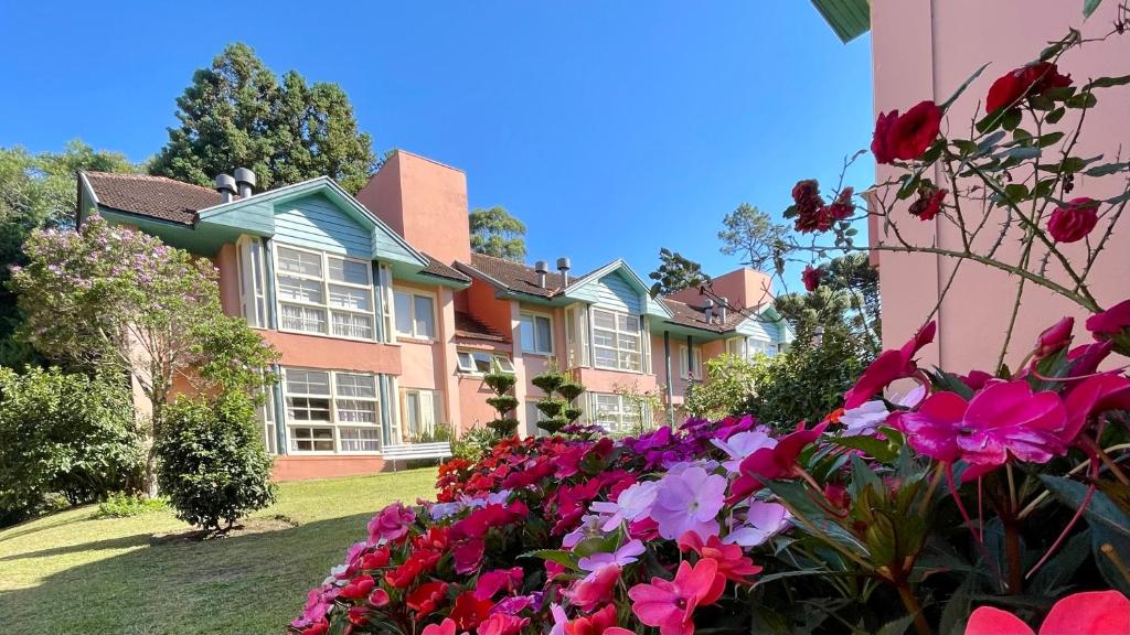 a large house with flowers in the yard at Apartamento c/LAREIRA CONDOMÍNIO, próx LAGO NEGRO in Gramado