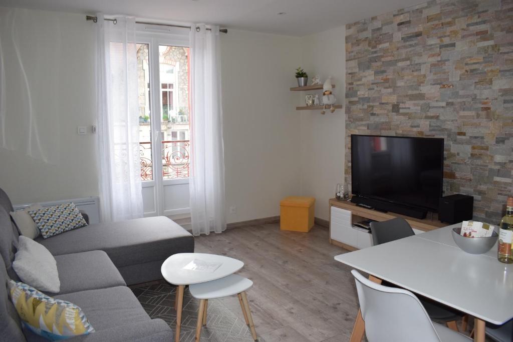 a living room with a couch and a tv at Superbe T3 classé 3 étoiles Chez Cathy et Frank situé en plein centre de Gérardmer in Gérardmer