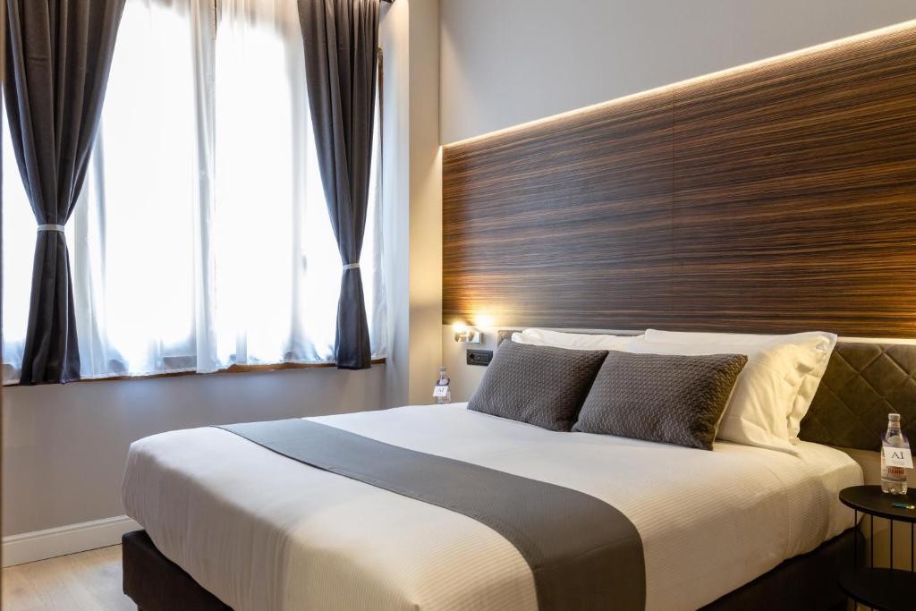 una camera con un grande letto con testiera in legno di Aiello Hotels - Duomo a Milano