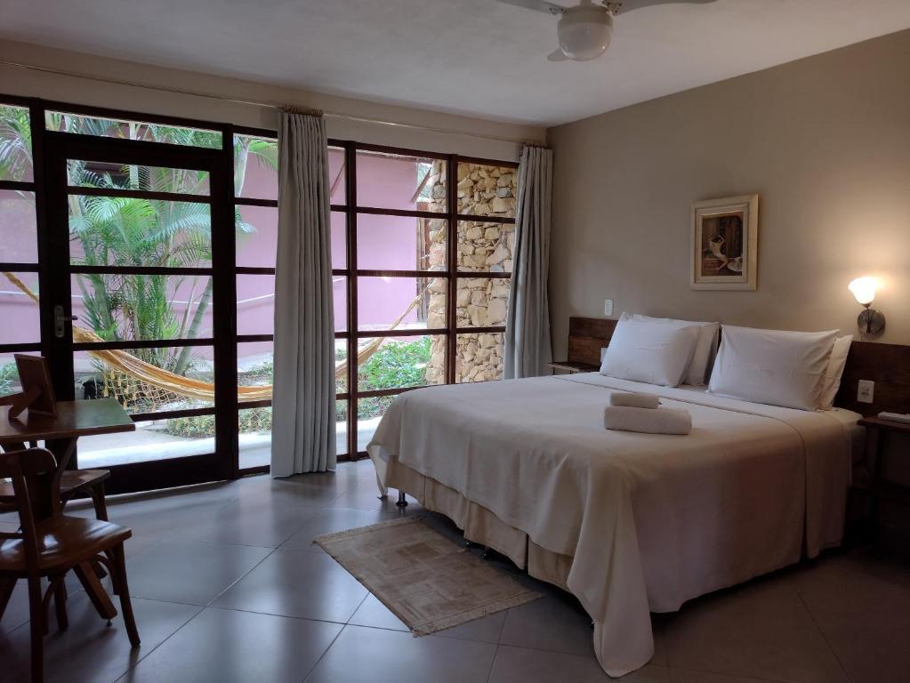 a bedroom with a large bed and a large window at Pousada Zazen in Vale do Capao