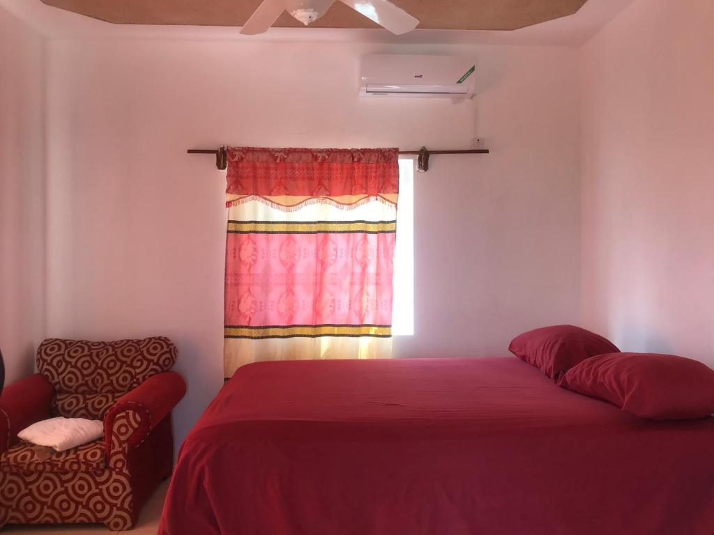 a bedroom with a red bed and a window at Quiet Escape Long Bay in Port Antonio