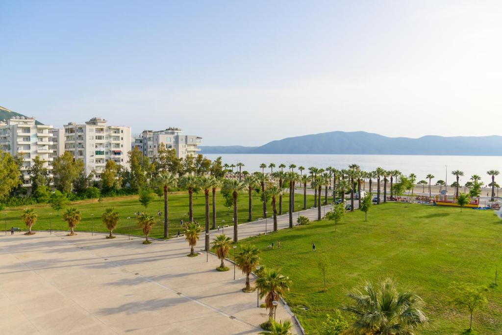 un parque con palmeras, edificios y agua en DANTE APARTAMENT, en Vlorë