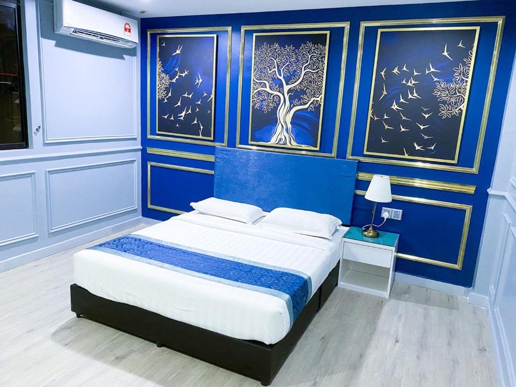 a bedroom with blue walls and a bed with a nightstand at 61 Hotel in Gua Musang