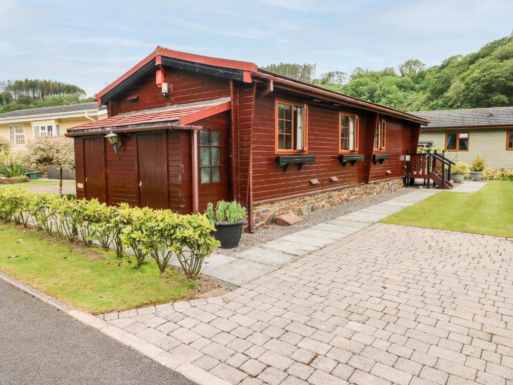 ein Holzhaus mit einer steinernen Einfahrt davor in der Unterkunft Heritage Park in Narberth