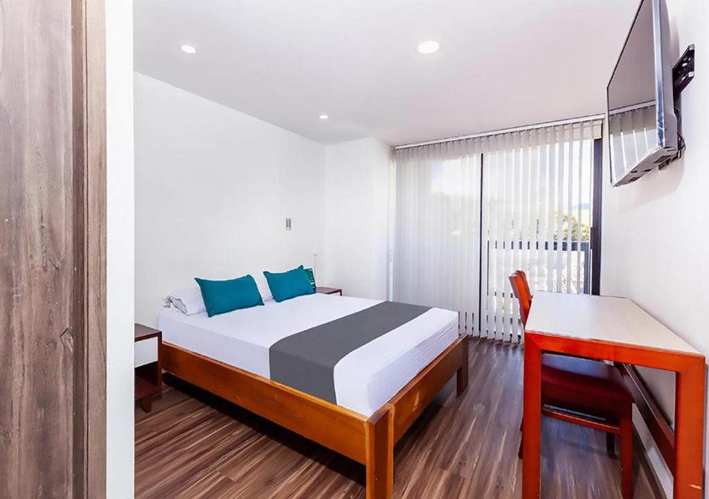 1 dormitorio con cama, escritorio y ventana en Hotel Basan Plaza en Pasto
