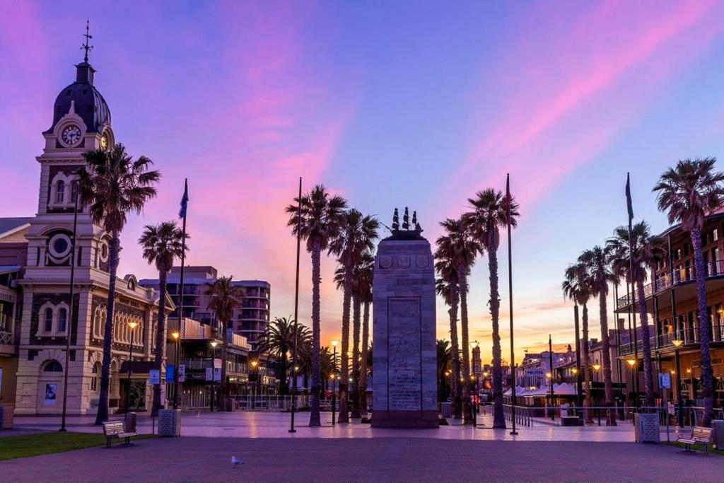 una torre dell'orologio di fronte a un edificio con palme di The Heart of Glenelg a Glenelg