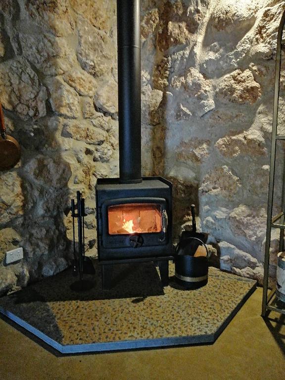 a stone wall with a stove in a room at Maunder Cottage Aldinga Township in Aldinga