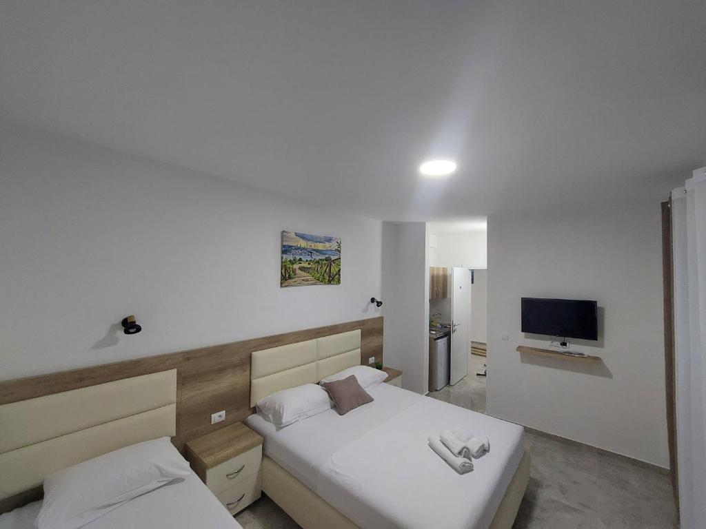 a bedroom with two beds and a flat screen tv at Apartments kupi ul rudaj 41 in Ulcinj