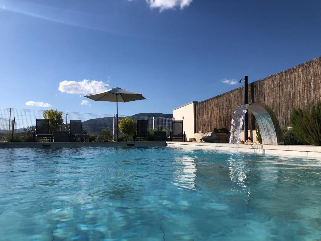 una piscina con una fuente y una sombrilla en Casa Chirreas, en Caravaca de la Cruz