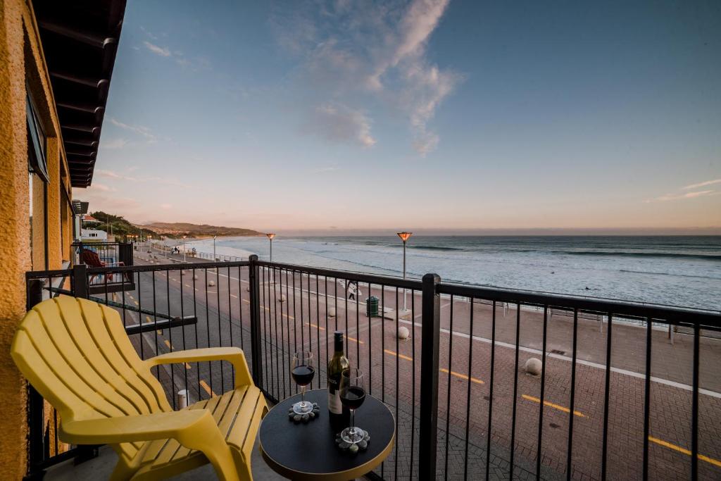 balcón con mesa y sillas y la playa en Esplanade Apartments, en Dunedin