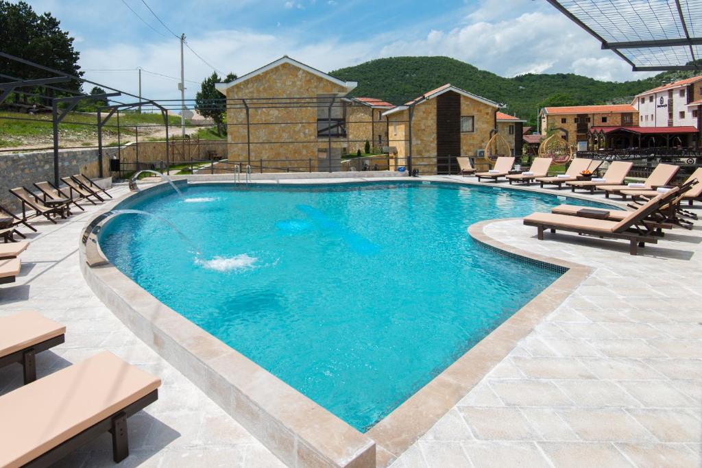 a large swimming pool with lounge chairs at Ethno Village St George in Cetinje