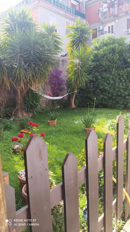 a fence in front of a garden with plants at Holiday rooms with private bathroom in Acilia