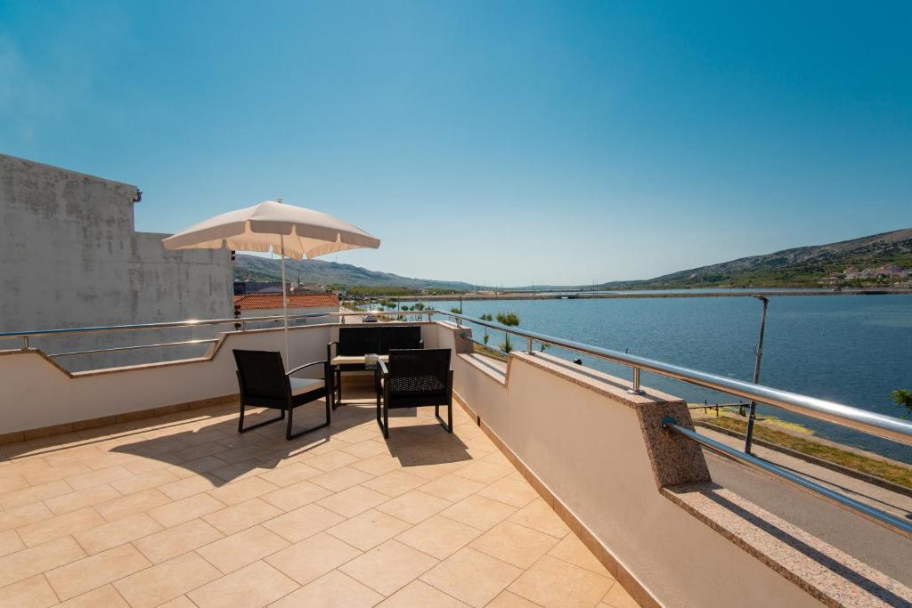 a balcony with a table and chairs and an umbrella at Apartment Lazić Pag by Pag tours in Pag