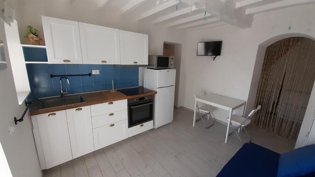 - une cuisine avec des placards blancs, un évier et une table dans l'établissement MaRosa, à Montignoso