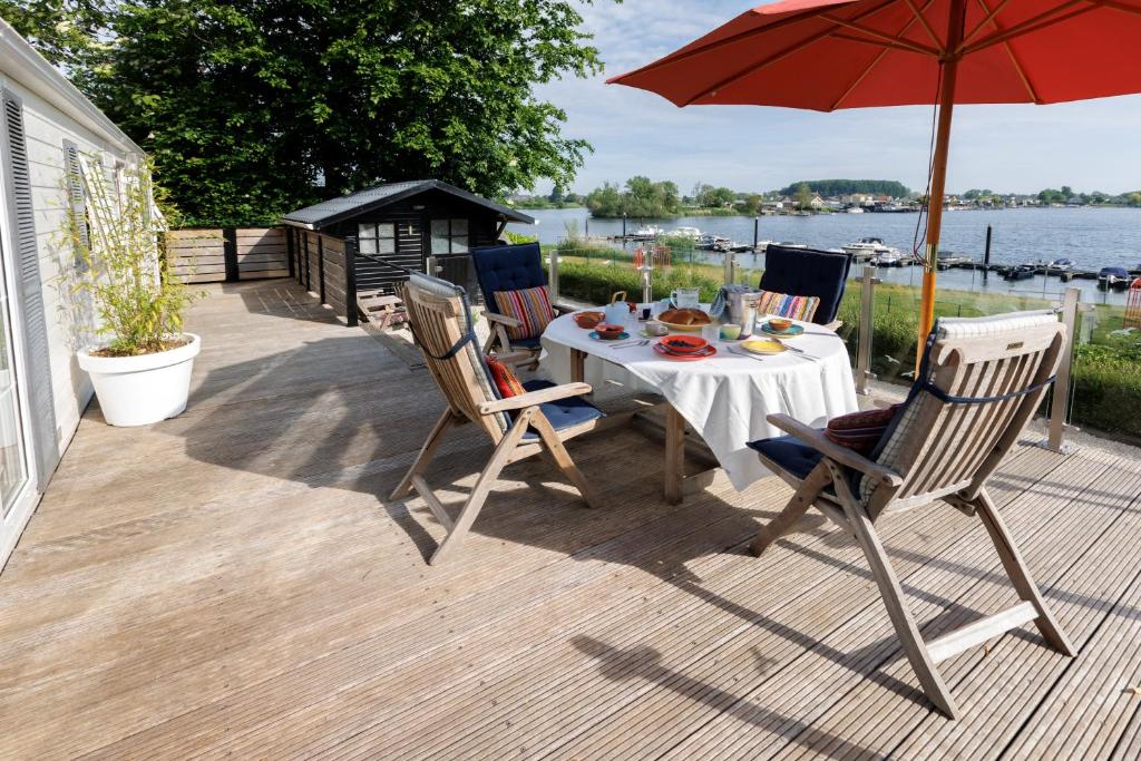 une terrasse avec une table, des chaises et un parasol dans l'établissement Mooi huisje aan de Maas, à Op-Andel