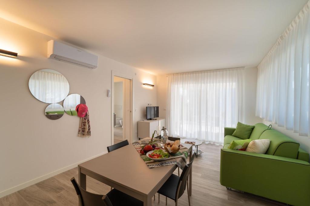 a living room with a table and a green couch at Zero5.Zero5 in Lignano Sabbiadoro