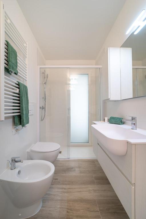 a white bathroom with two sinks and a shower at Zero5.Zero5 in Lignano Sabbiadoro