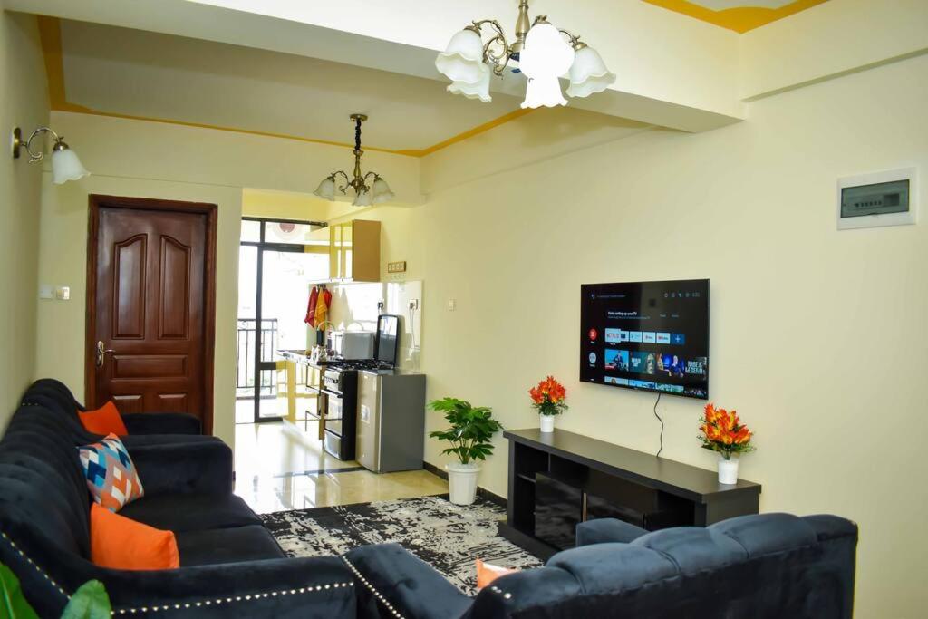 a living room with two blue couches and a flat screen tv at The Perfect Retreat Apartment with great view. in Nairobi