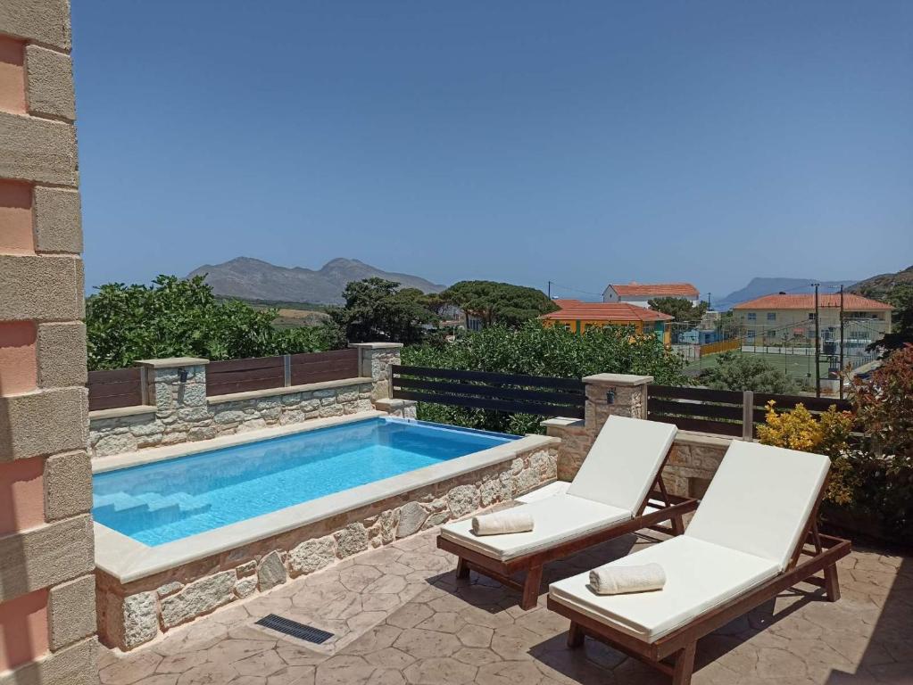 a swimming pool with two white chairs and a swimming pool at Estia in Plátanos