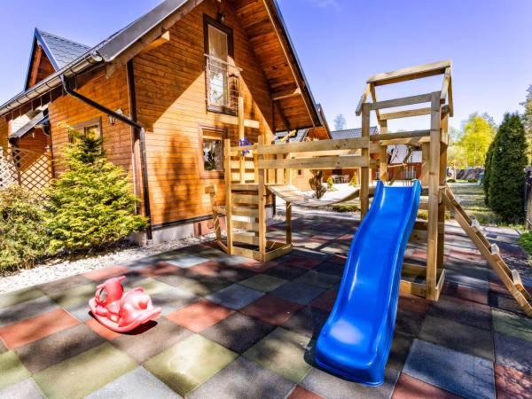 a playground with a slide and a bunk bed in front of a house at Resort EDEN domki, apartamenty i pokoje in Jastrzębia Góra