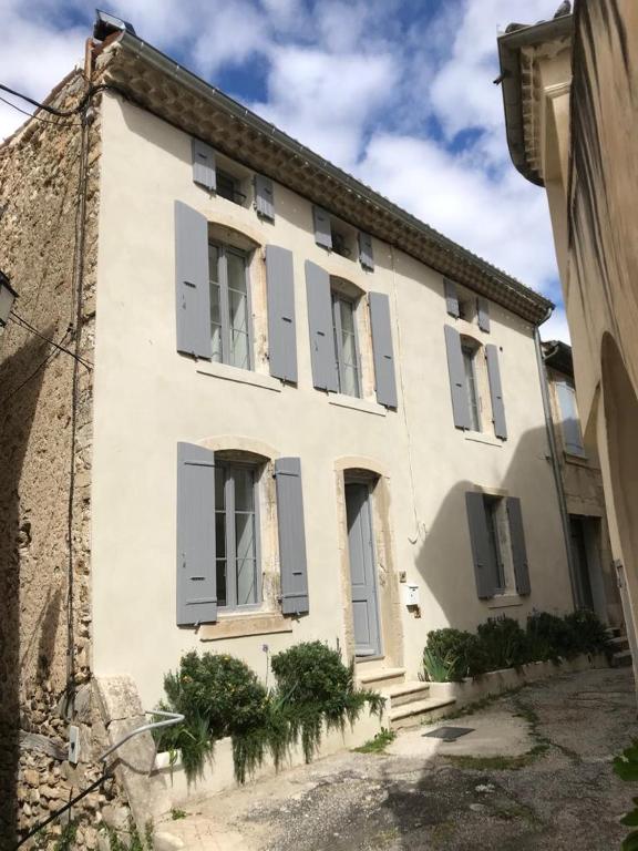 un grand bâtiment blanc avec volets gris dans l'établissement Maison Delière, à Venterol