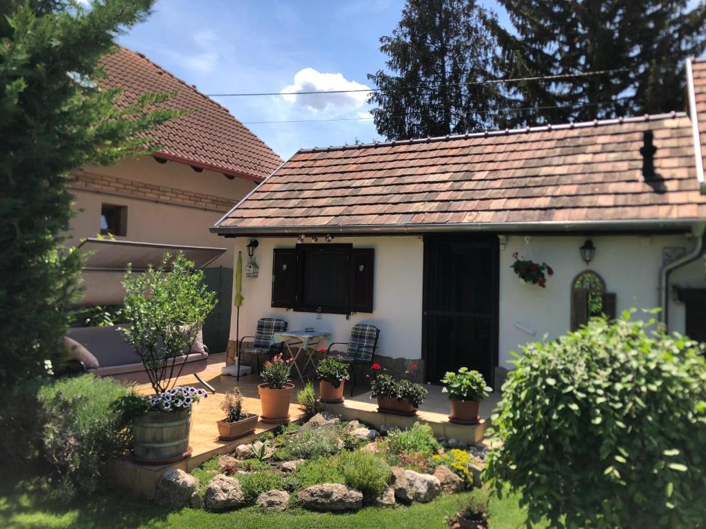 une petite maison blanche avec des plantes en pot dans une cour dans l'établissement CSAOL Apartman ház, à Velence