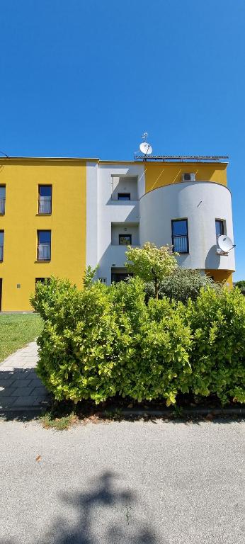 un bâtiment jaune et blanc avec des buissons devant lui dans l'établissement Oaza Klara, à Karlovac