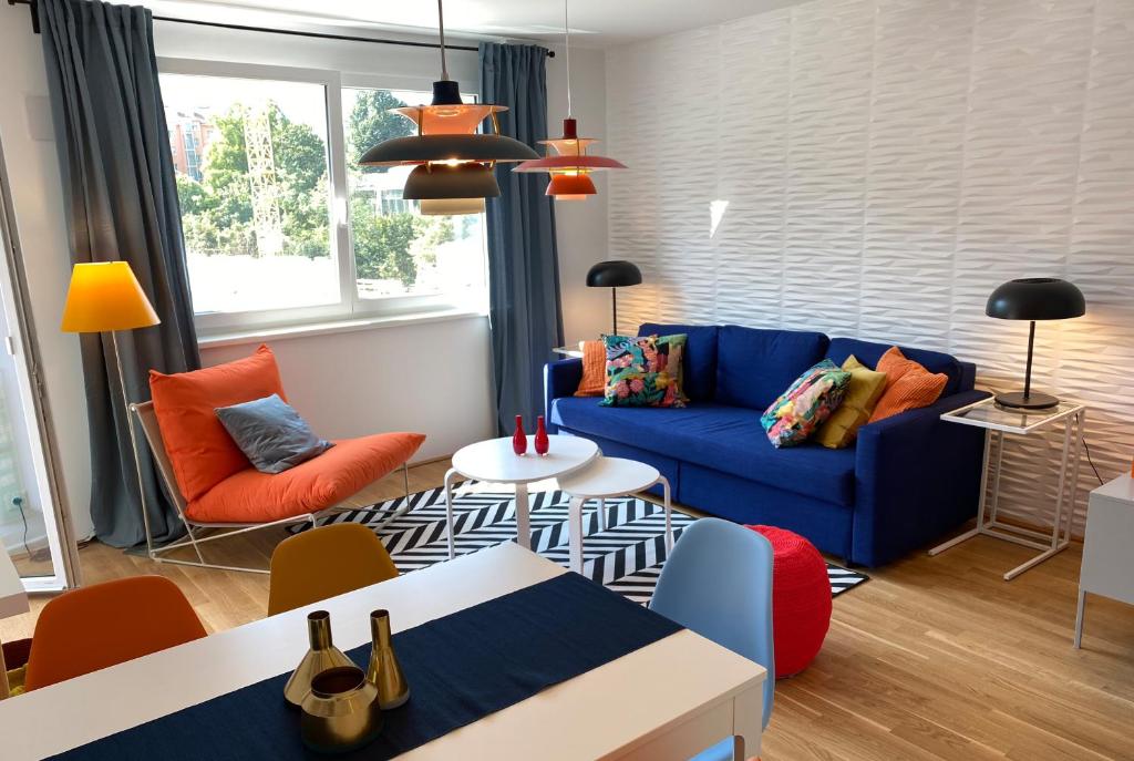 un soggiorno con divano blu e sedie arancioni di Brand New Cozy Apartment 10 min to city center a Vienna