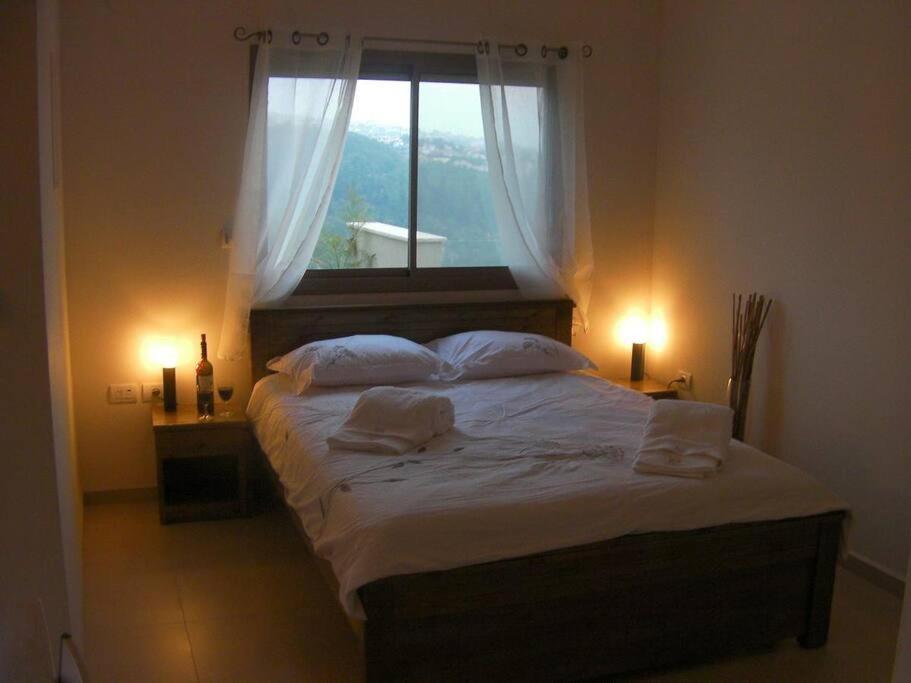 um quarto com uma cama com duas almofadas e uma janela em ROSEHILLS em Kefar Weradim