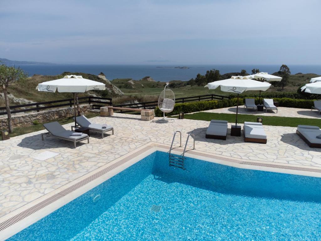 a swimming pool with chairs and umbrellas next to at Tramonto Suites in Xi