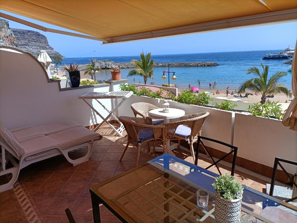 einen Balkon mit einem Tisch und Stühlen sowie Strandblick in der Unterkunft Mogán suite in Puerto de Mogán