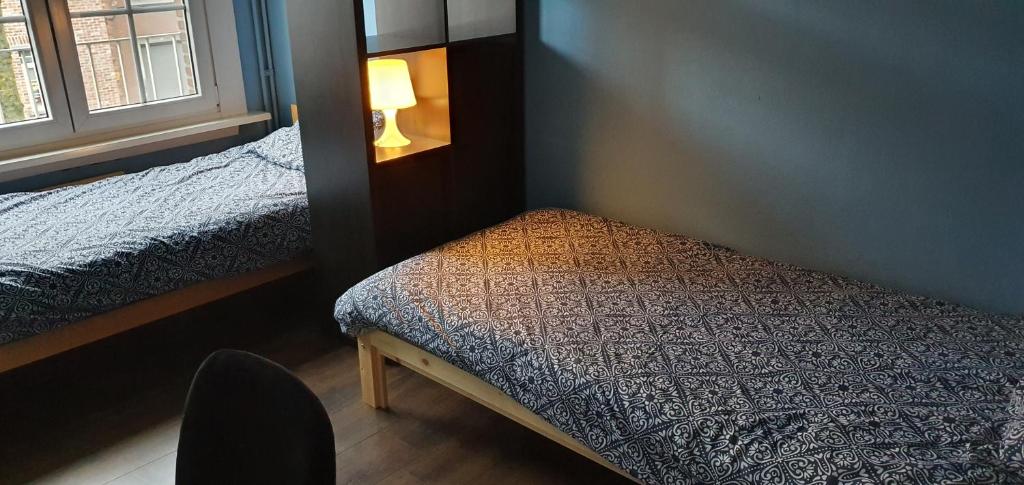 a bedroom with two beds and a lamp on the wall at ROOM WITH 2 SEPARATED BEDS in Mortsel