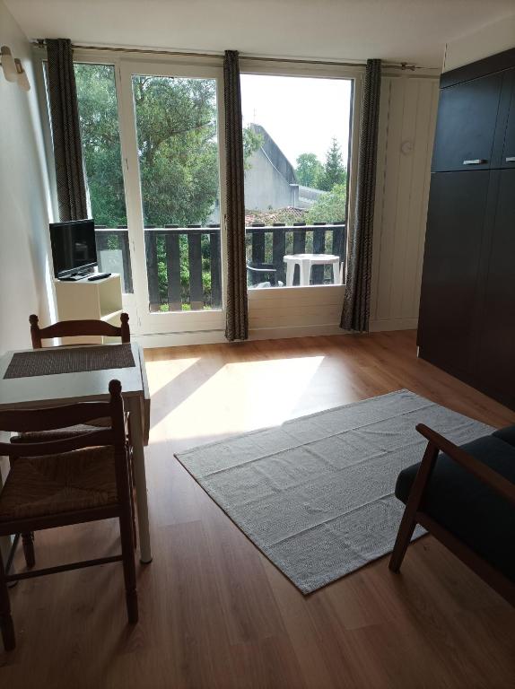 un salon avec une table et une grande fenêtre dans l'établissement Studio tout confort au bord du lac d'Estey, à Dax