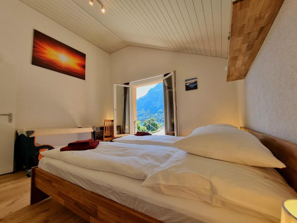 a bedroom with a large bed with a large window at Seeparadiesli am schönen Thunersee in Därligen