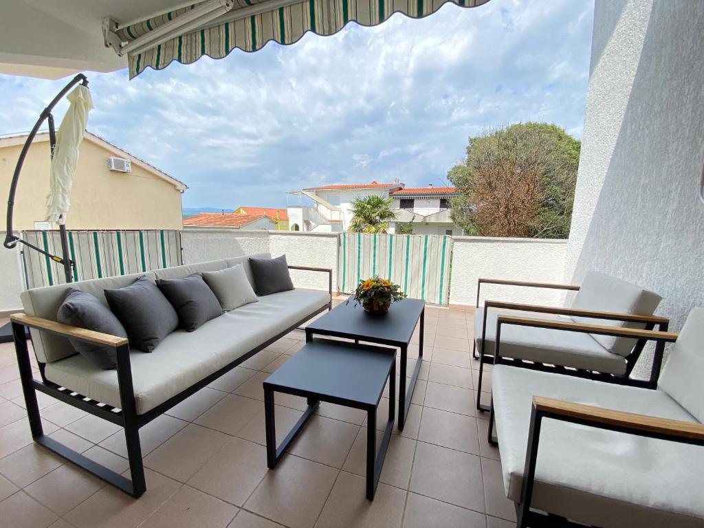 a living room with a couch and tables on a balcony at Jandom in Malinska