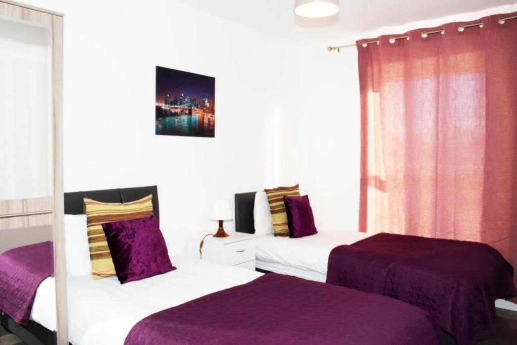 - 2 lits dans une chambre d'hôtel avec des draps violets dans l'établissement TMS Beautiful 2BR Apartment! Ensuite! Lakeside, à West Thurrock