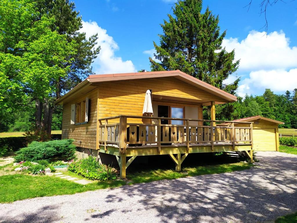 een klein huis met een veranda en een terras bij Chalet du Spièmont in Champdray