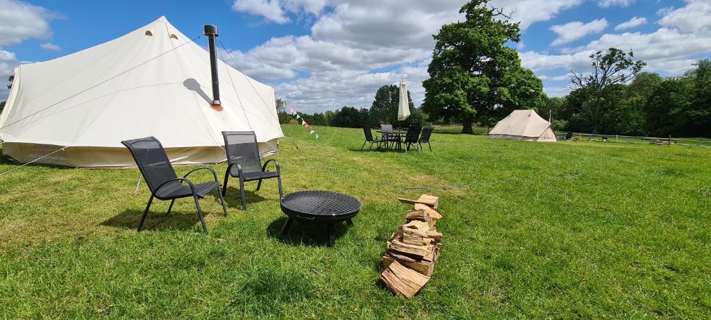 eine Gruppe von Stühlen, einem Grill und einem Zelt in der Unterkunft Park Farm Holidays Glamping in Lyndhurst