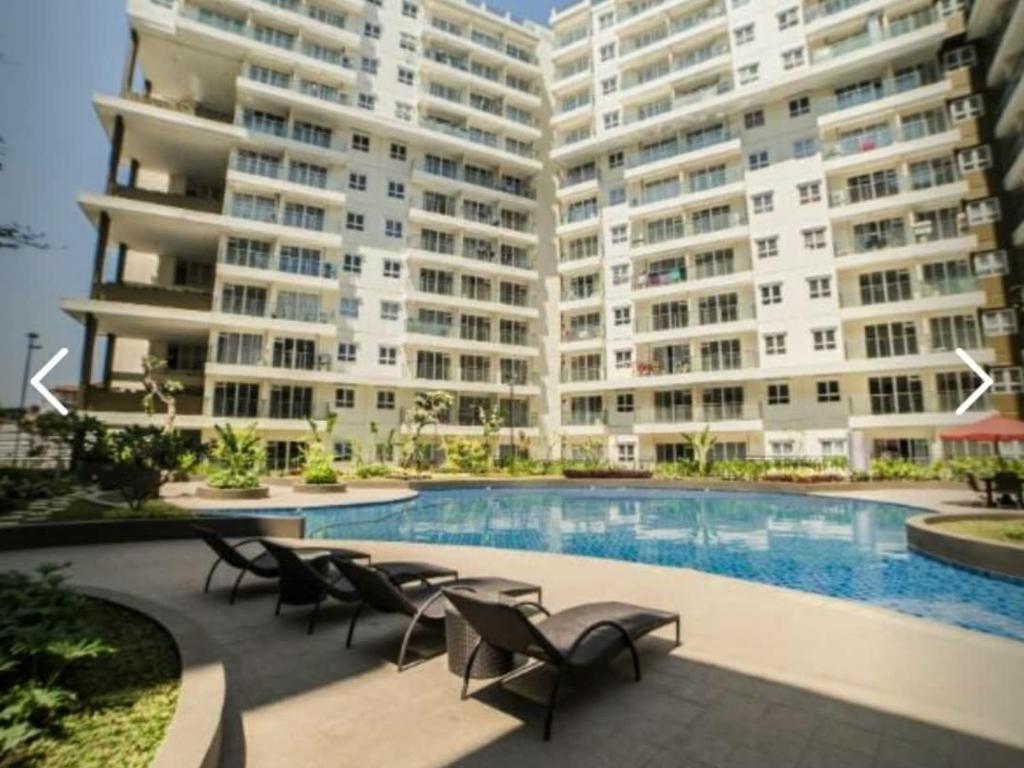 un gran edificio de apartamentos con piscina y sillas en Apartment Gateway pasteur en Bandung