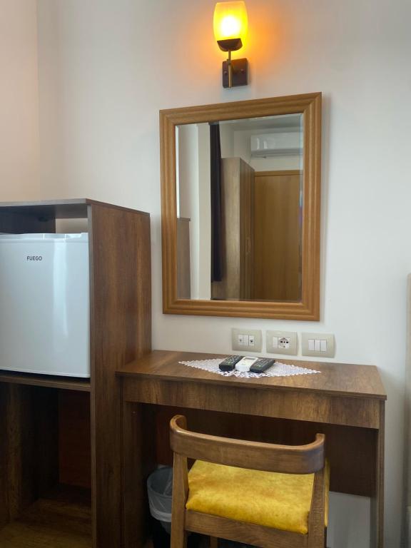 uma casa de banho com um toucador, um espelho e uma cadeira. em Hotel Republika Berat em Berati