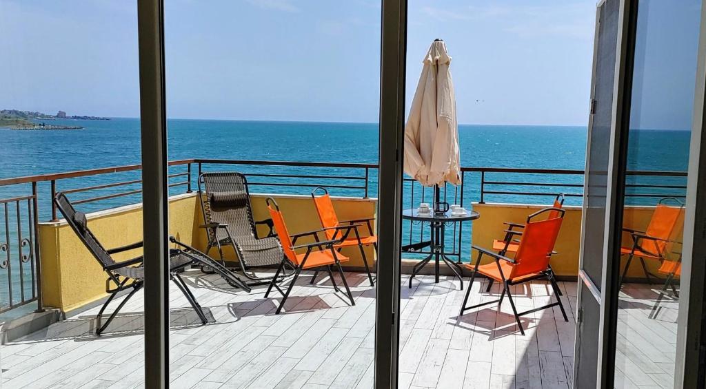 a balcony with chairs and a table and an umbrella at AKB Apartment Sea View in Aheloy