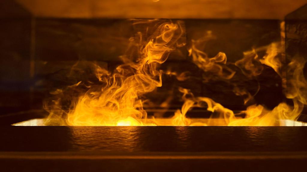 Ein Feuer kommt aus dem Ofen in der Unterkunft Landhaus Mader Hintertux in Tux