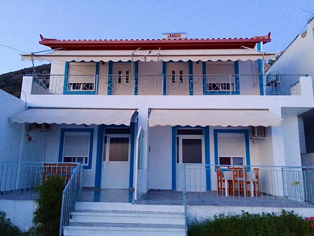 a white house with blue trim and chairs on the balcony at Vila Gusti in Borsh