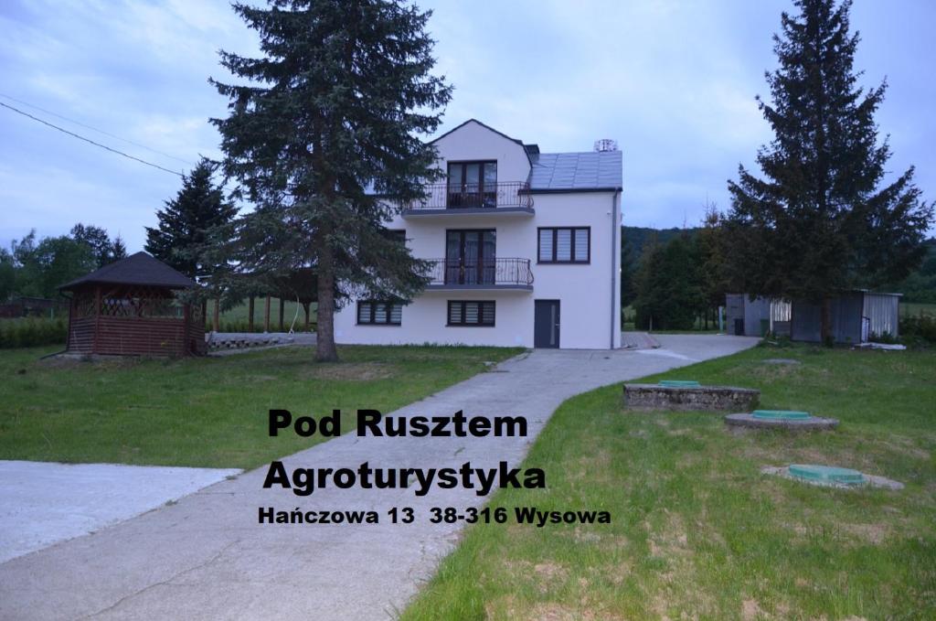uma casa branca com uma árvore em frente em Pod Rusztem Agroturystyka em Wysowa-Zdrój