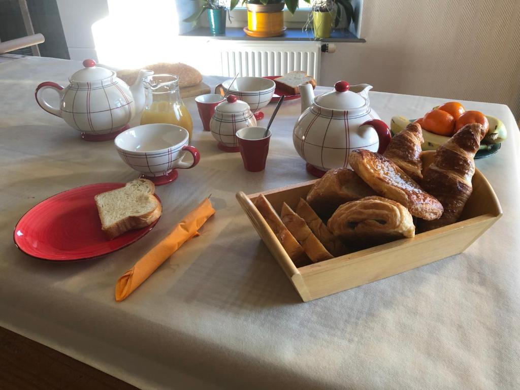 una mesa con una bandeja de pan y un plato de comida en La maison bleue, en Altenbach