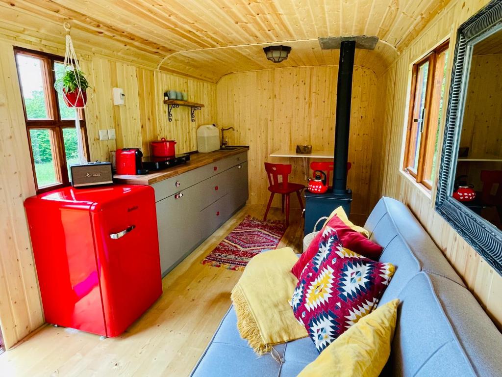 ein Wohnzimmer mit einem blauen Sofa und einem roten Kühlschrank in der Unterkunft Maringotka Lipenka u Lipenské přehrady na Šumavě in Hořice na Šumavě