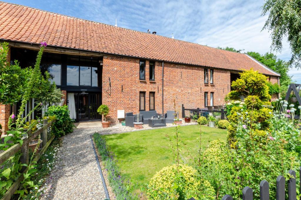 a brick house with a garden in front of it at Chestnut Barn Runham 1880's Barn conversion 
