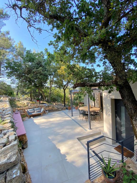 une terrasse avec un arbre, une table et des chaises dans l'établissement Maison au calme au milieu des restanques, à Cuers