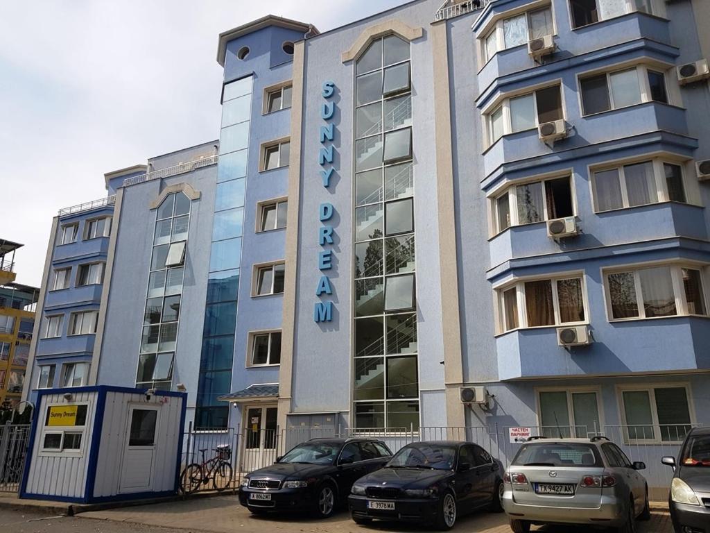 een groot gebouw met auto's geparkeerd voor het bij Sunny Dream Apartments Sunny Beach Bulgarien Sonnenstrand in Sunny Beach