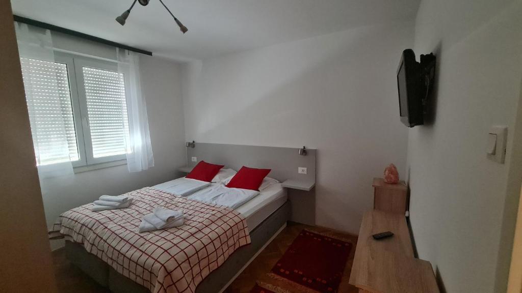 ein kleines Schlafzimmer mit einem Bett mit roten Kissen in der Unterkunft Sara in Mostar
